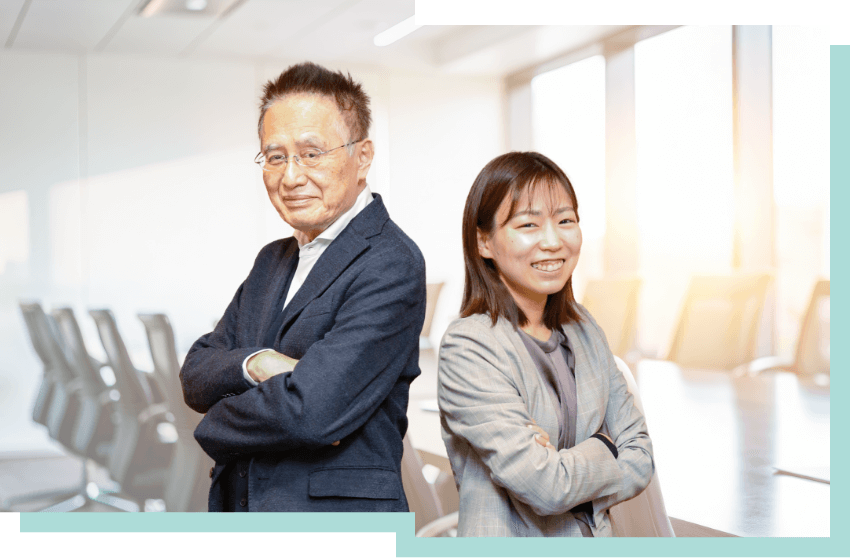  「INA新建築研究所の再開発部門で活躍するベテランと若手社員」― オフィスで笑顔を見せる2人の社員。まちづくりの総合コーディネーターとして、再開発事業の設計とコンサルティングを担うINAらしさを語るインタビュー。